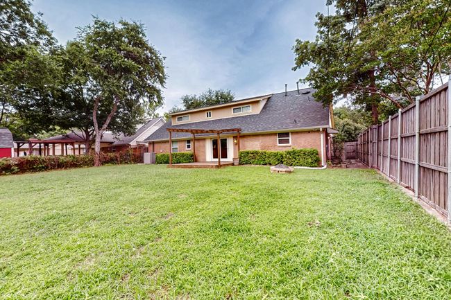 Back of property featuring a fenced backyard, a pergola, and a shingled roof | Image 35