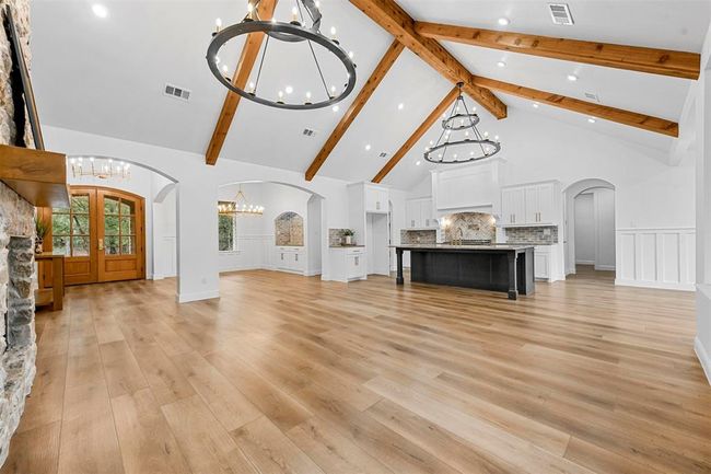 Unfurnished living room with an inviting chandelier, beam ceiling, high vaulted ceiling, and light wood-type flooring | Image 11