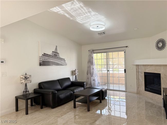 Living area with a tile fireplace, marble finish floor, vaulted ceiling, visible vents, and baseboards | Image 9