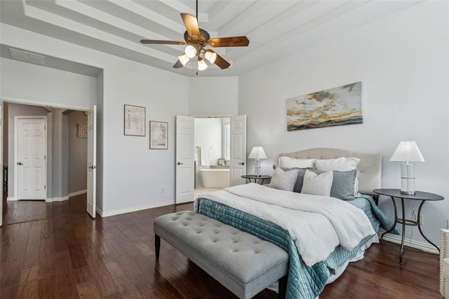 Bedroom with ensuite bath, ceiling fan, a tray ceiling, and dark wood-type flooring | Image 15