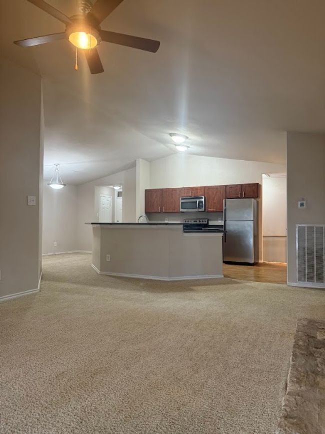 Kitchen featuring stainless steel appliances, dark countertops, open floor plan, light carpet, and vaulted ceiling | Image 13