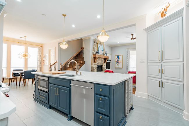 Kitchen with stainless steel appliances, blue cabinets, ornamental molding, light tile patterned floors, and a fireplace | Image 7