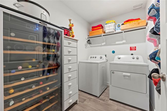 The spacious laundry room offers plenty of room for both functionality and organization. It features a shelf for convenient storage, perfect for detergents, cleaning supplies, or other essentials. There’s also ample space to fit an extra fridge, making it a practical addition for storing beverages or extra groceries. The room is well-designed to keep everything tidy and easily accessible, adding to the overall efficiency of the home. | Image 17