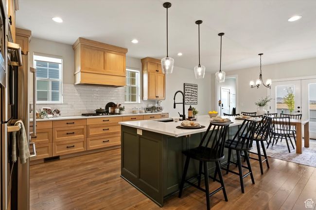 Kitchen featuring a kitchen island with sink, light countertops, a sink, light brown cabinets, and a breakfast bar | Image 11
