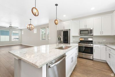 Kitchen with stainless steel appliances, a healthy amount of sunlight, sink, and a kitchen island with sink | Image 2