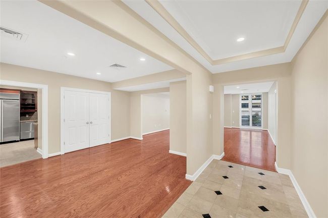 The inviting view as you enter the home. Marble floors and tray inset ceiling of Entry Hallway give a sense of separation from the Dining Room on left and large Living Room in background. Double doors on left are HVAC closet. | Image 12