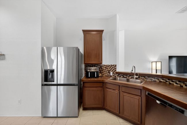 Kitchen featuring appliances with stainless steel finishes, tasteful backsplash, light tile patterned flooring, and brown cabinets | Image 29