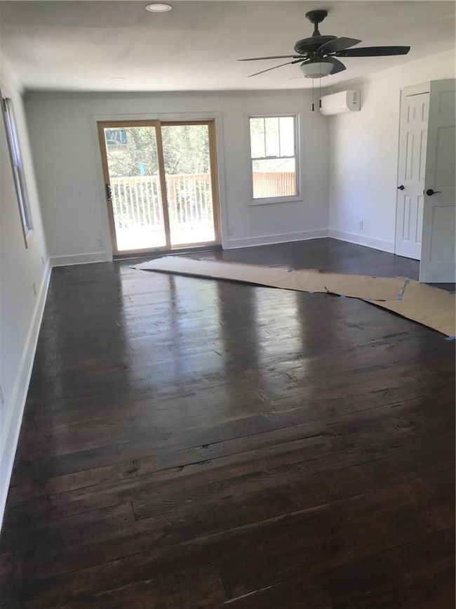 Empty room featuring dark wood-type flooring, a wall unit AC, and ceiling fan | Image 20