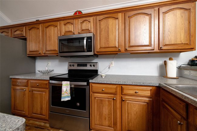 Kitchen with stainless steel appliances and brown cabinetry | Image 18