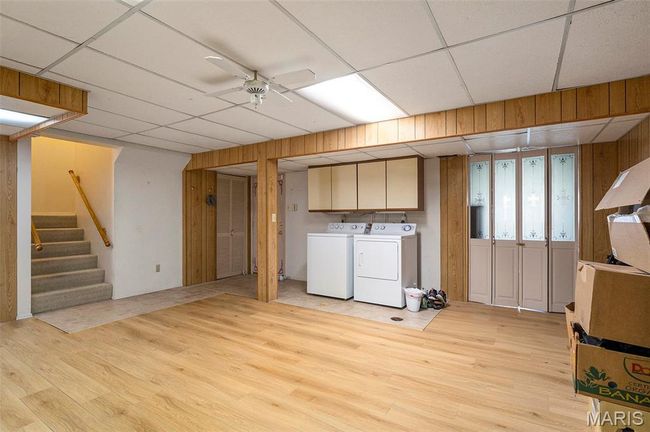 Finished basement with separate washer and dryer, a paneled ceiling, light wood-type flooring, a ceiling fan, and stairway | Image 20