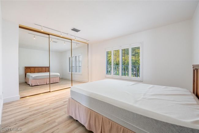 Bedroom with mirrored closet and planation shutters. | Image 23
