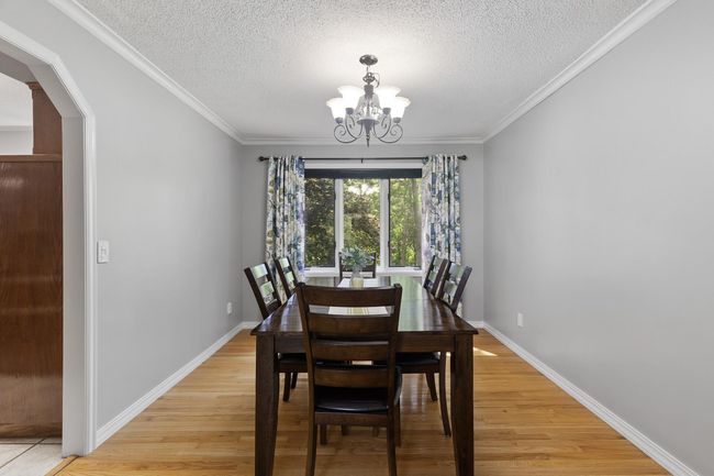 Elegant dining room with gleaming hardwood floors, updated light fixtures, and a picturesque window showcasing beautiful backyard views. | Image 8