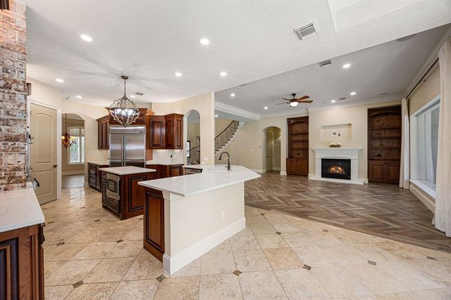 Kitchen is open to the living room and breakfast area with neutral paint tones and timeless warm wood cabinetry. | Image 10