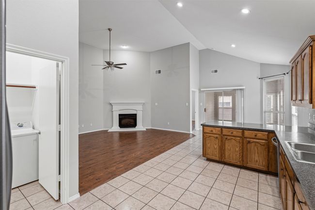 Kitchen with dark countertops, a peninsula, light tile patterned floors, lofted ceiling, and recessed lighting | Image 23