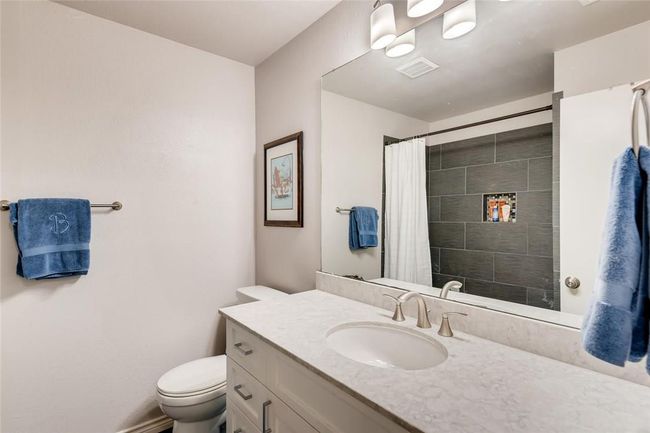 Bathroom featuring toilet, vanity, and curtained shower | Image 20