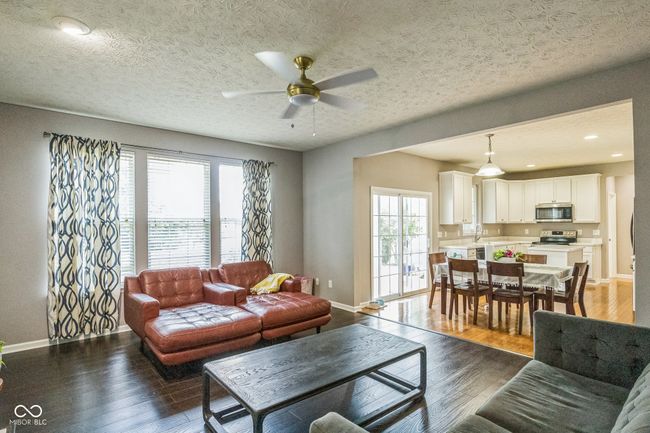 living room featuring a ceiling fan, healthy amount of natural light, wood finished floors, and a textured ceiling | Image 6