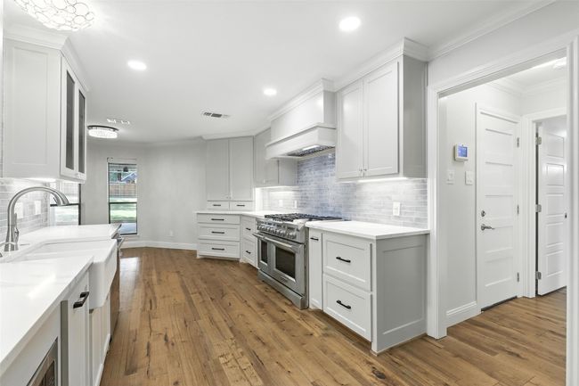 Kitchen featuring high end stainless steel range oven, wood-type flooring, white cabinets, tasteful backsplash, and recessed lighting | Image 15
