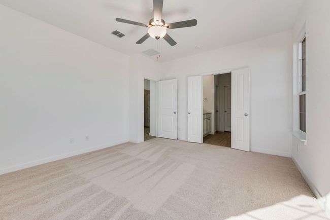 Unfurnished bedroom with light colored carpet, ensuite bath, and a ceiling fan | Image 11