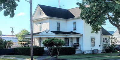 Street view of front facade with a porch, central AC, and a front yard | Image 1