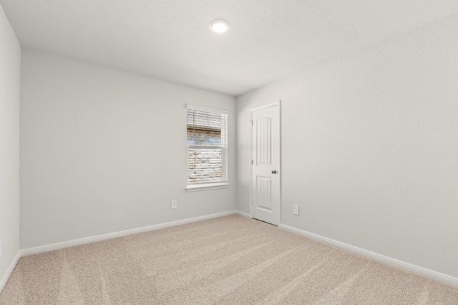 Bedroom featuring light colored carpet and baseboards with closet door. | Image 15