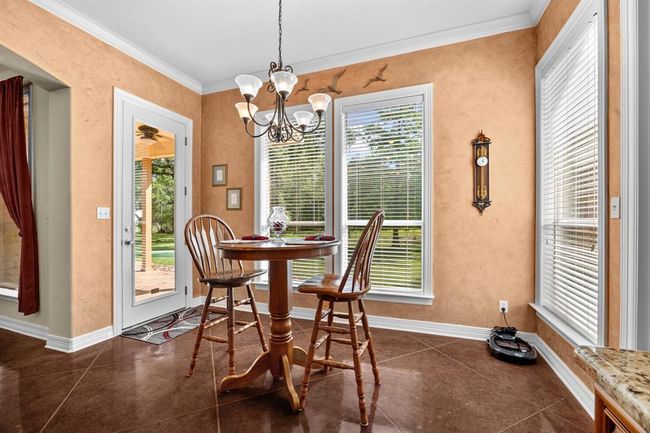 Warm textured walls, a decorative chandelier and windows create an intimate spot for morning coffee, with direct access to the covered patio and backyard. | Image 14