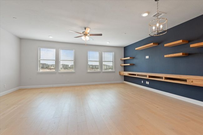 Empty room featuring ceiling fan with notable chandelier, light hardwood / wood-style floors, and plenty of natural light | Image 15