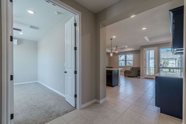 Corridor with a tray ceiling, recessed lighting, light carpet, and light tile patterned flooring | Image 7