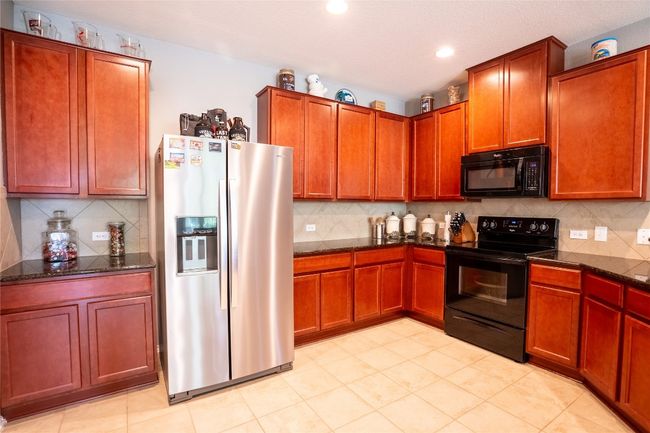 Kitchen featuring black appliances, decorative backsplash, dark stone counters, and recessed lighting | Image 4