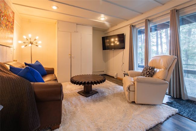 Living area featuring a chandelier, wood finished floors, a baseboard heating unit, and a healthy amount of sunlight | Image 10