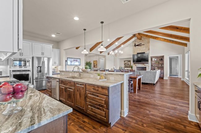 Kitchen featuring a sink, lofted ceiling with beams, a kitchen island with sink, ceiling fan, and stainless steel appliances | Image 13
