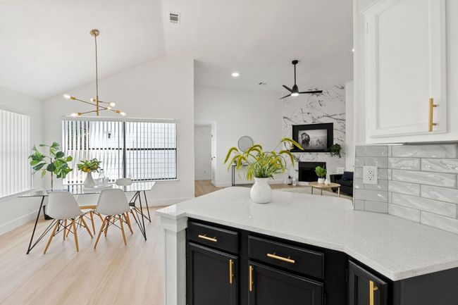 Kitchen with dark cabinetry, ceiling fan with notable chandelier, and a fireplace | Image 17