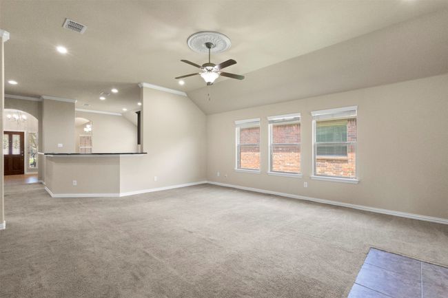 Unfurnished living room featuring a ceiling fan, carpet floors, ornamental molding, recessed lighting, and arched walkways | Image 11