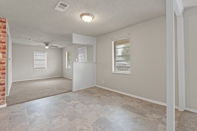 Spare room featuring a textured ceiling, ceiling fan, light carpet, and light stone finish floors | Image 6
