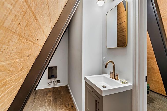 This photo showcases a cozy A-frame room with wooden walls and flooring, featuring a ceiling fan and a window providing a view of greenery outside. Ideal for a unique, rustic retreat. | Image 23