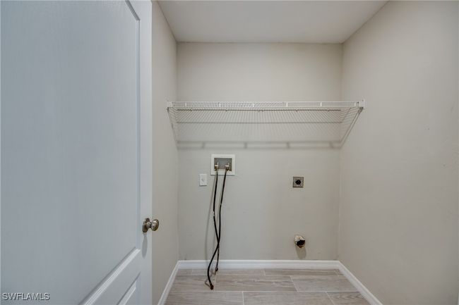 Washroom with wood finish floors, hookup for a washing machine, electric dryer hookup, laundry area, and baseboards | Image 43