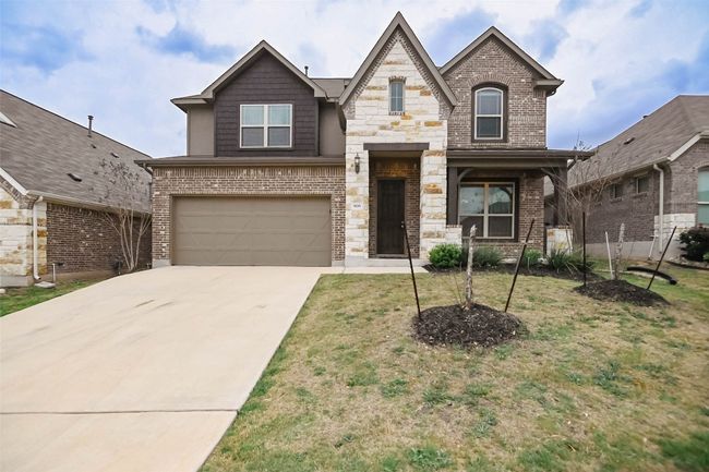 View of front of house featuring stone siding, an attached garage, a front yard, brick siding, and​​‌​​​​‌​​‌‌​‌‌​​​‌‌​​‌‌​‌​​​​​‌ driveway | Image 4