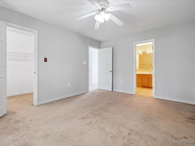 Unfurnished bedroom with light carpet, a walk in closet, ensuite bathroom, ceiling fan, and a closet | Image 19