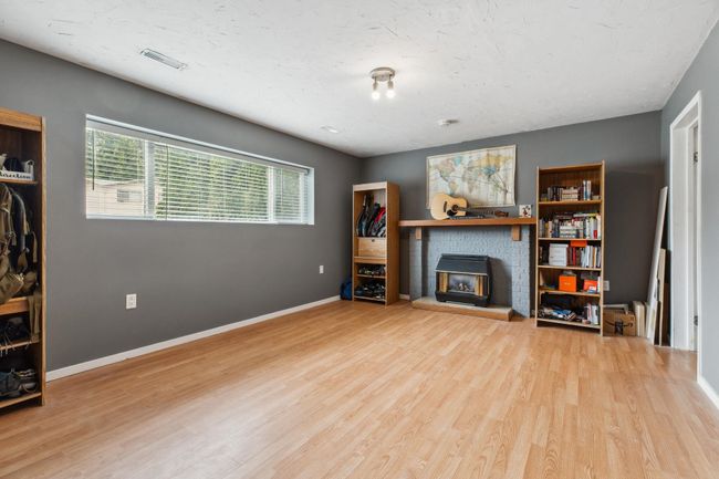Unfurnished living room featuring wood finished floors, baseboards, visible vents, and a brick fireplace | Image 18