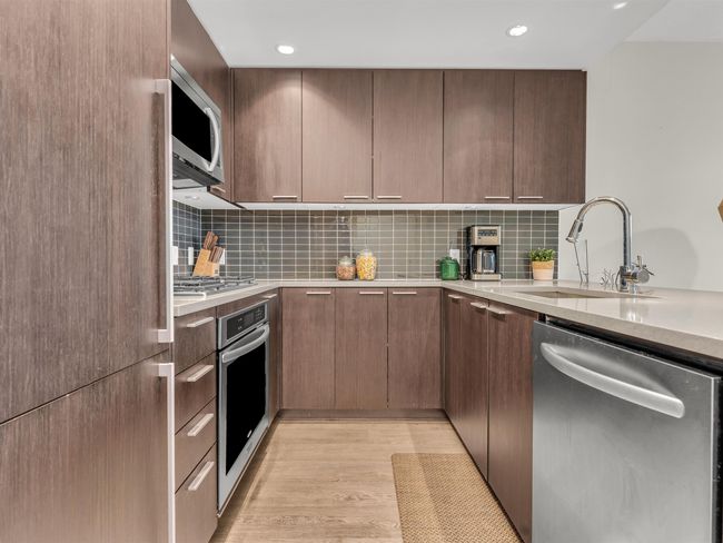 Kitchen with a sink, decorative backsplash, light wood-style floors, stainless steel appliances, and light countertops | Image 10