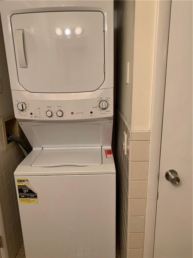 1st Fl Laundry area with tile walls and stacked washing maching and dryer | Image 19