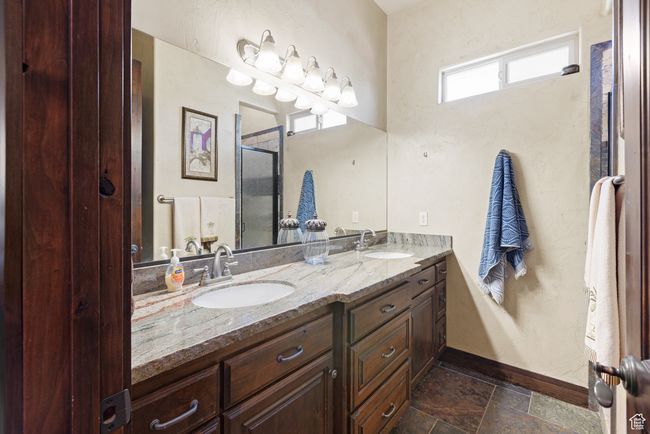 Bathroom featuring double vanity, a shower with shower door, and stone finish flooring | Image 14