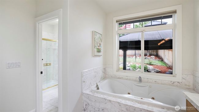 The en suite bathroom offers a spacious walk-in shower and separate toilet, a large soaking tub, and a huge window overlooking the backyard. | Image 12