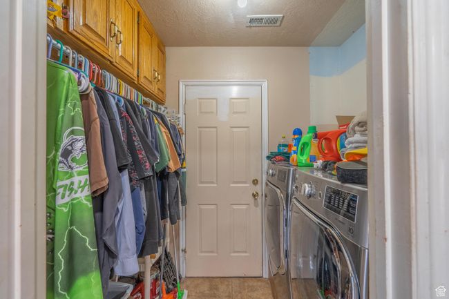 Washroom featuring independent washer and dryer, light tile patterned flooring, and a textured ceiling | Image 29