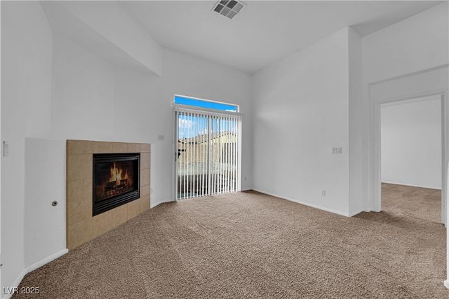 Unfurnished living room with a tiled fireplace, carpet floors, visible vents, and baseboards | Image 5
