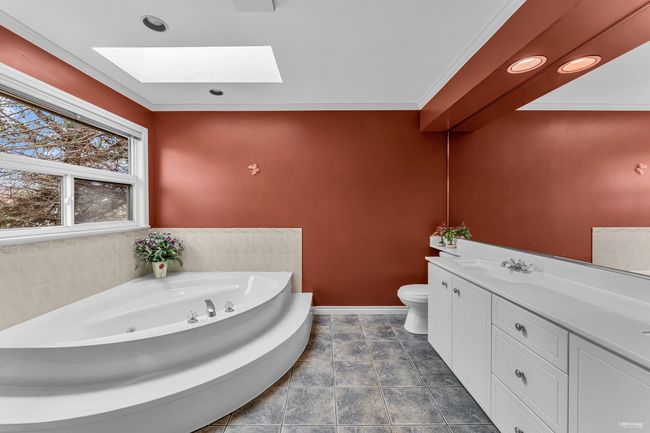 Full bath with crown molding, a garden tub, vanity, toilet, and a skylight | Image 19