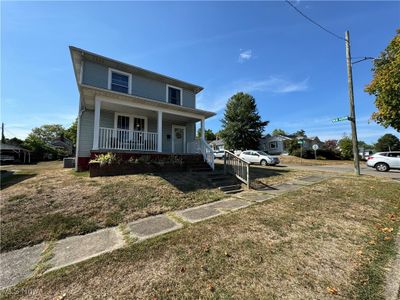 View of front of home with a front yard, central AC unit, and a porch | Image 1