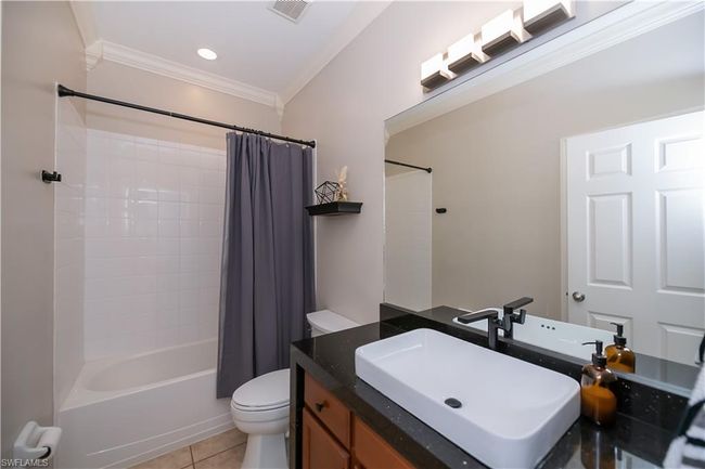 Full bathroom featuring shower / bath combo, toilet, tile patterned floors, visible vents, and ornamental molding | Image 20