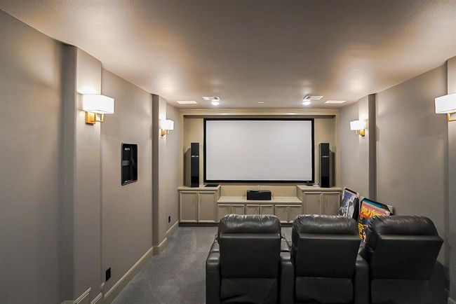 This photo showcases a cozy home theater room featuring a large screen, surround sound speakers, comfortable recliner seating, and soft ambient lighting, perfect for movie nights. | Image 37