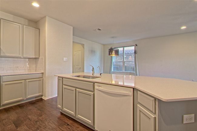 Kitchen featuring dishwasher, light countertops, dark wood-style flooring, backsplash, and recessed lighting | Image 17