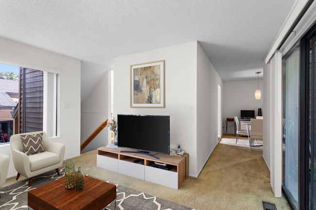 Carpeted living room with an office area and a textured ceiling | Image 9